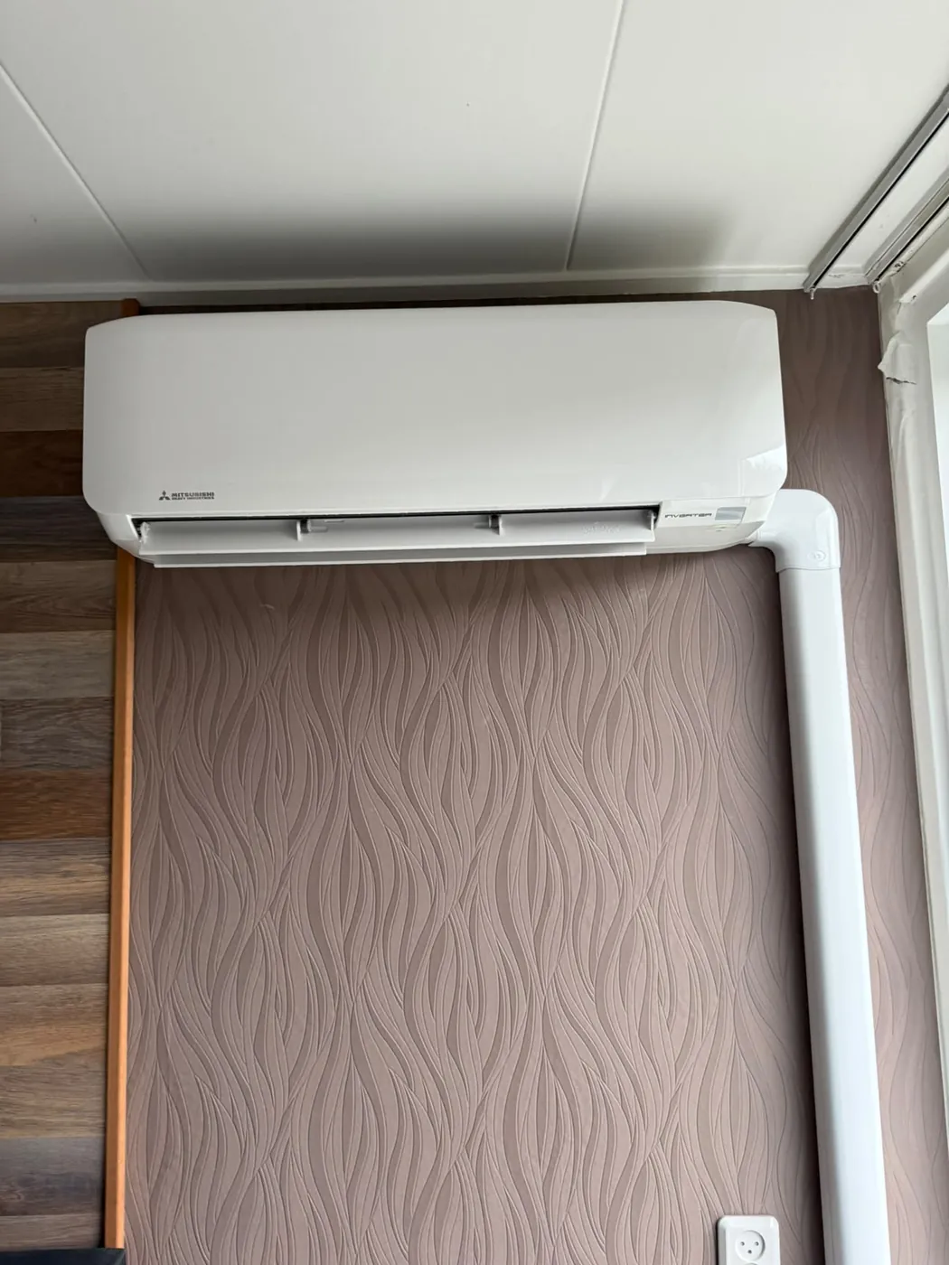 Witte airco binnenunit strak boven een raam geplaatst