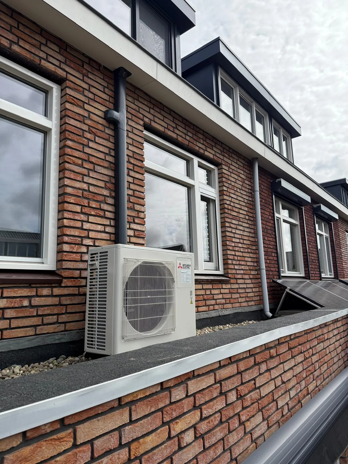 Zijaanzicht van een Mitsubishi Electric buitenunit en leidingwerk